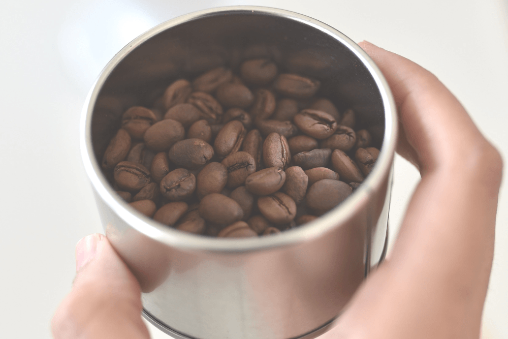 hand holding a cup of coffee beans